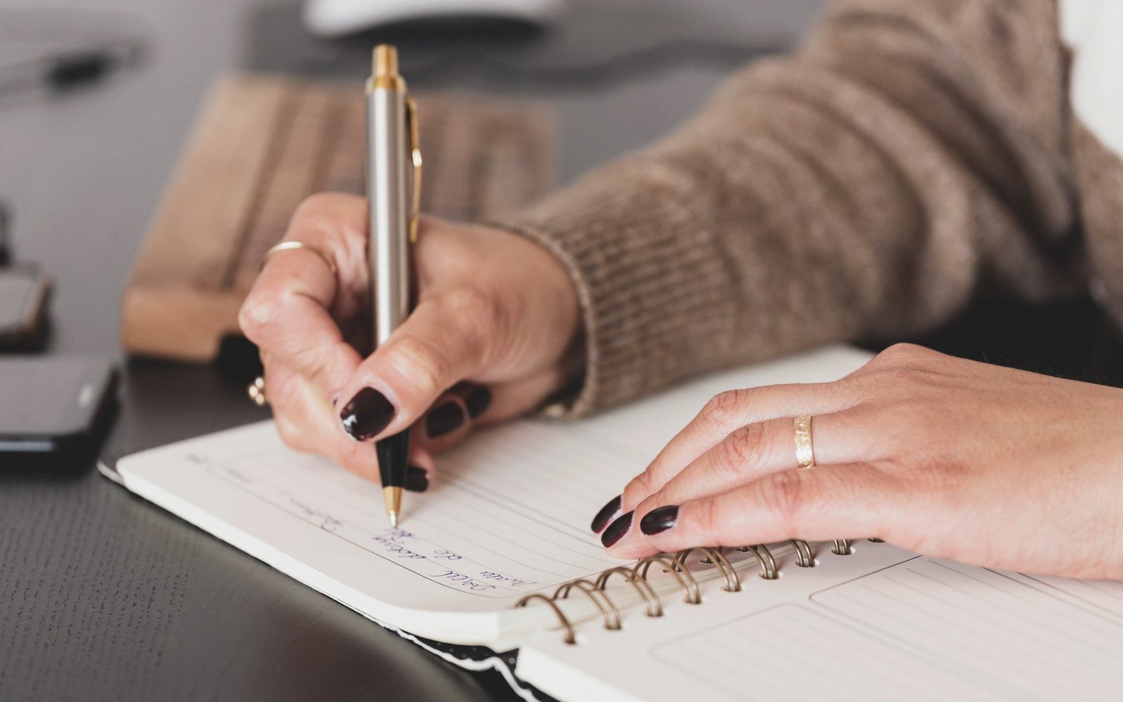 A person writing notes in a spiral notebook.