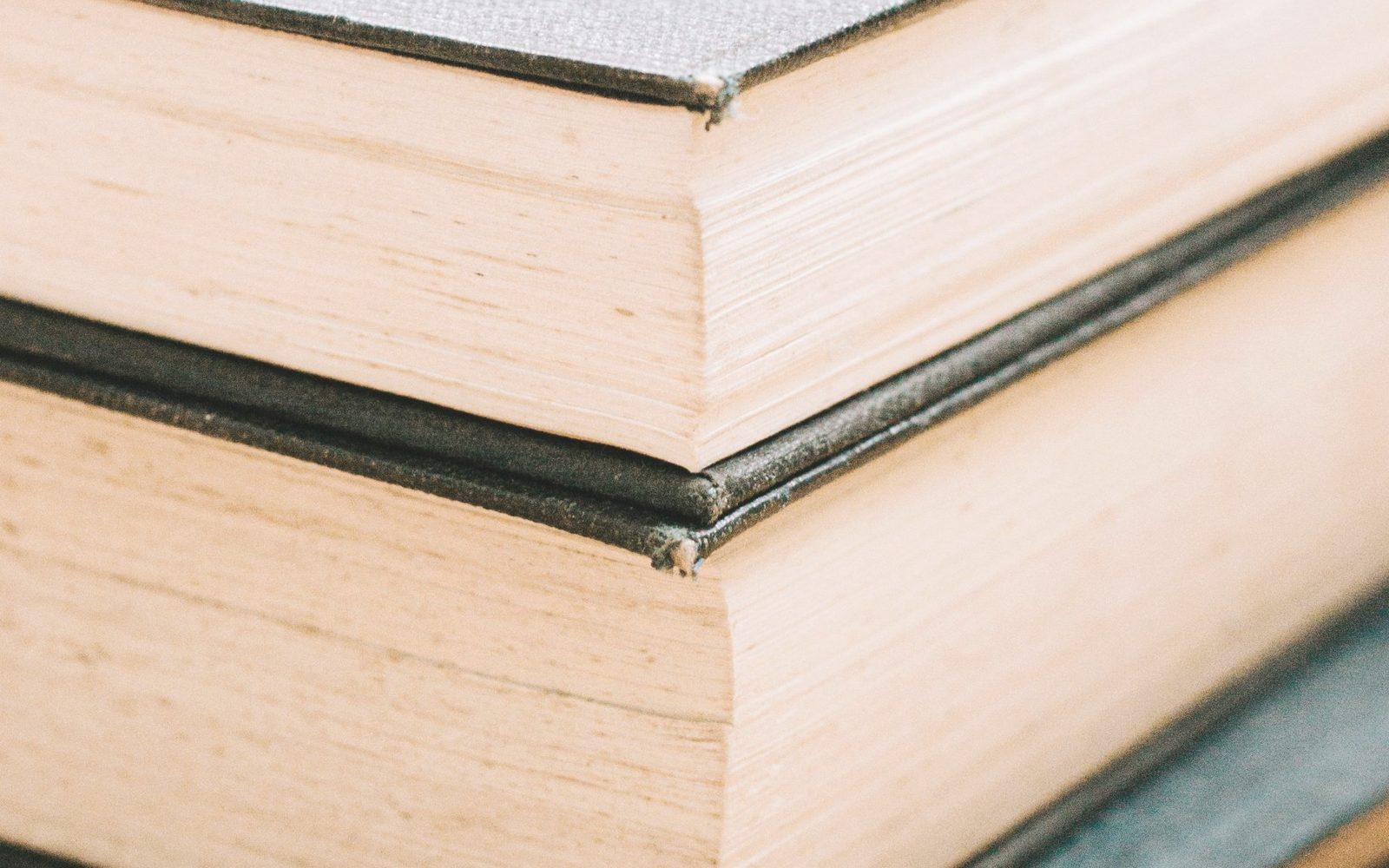 Close view of the edges of a stack of thick bound volumes.
